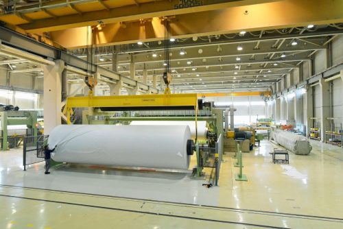 Industriehalle einer Papierfabrik: Papierrolle aus Altpapier in der Herstellung // production of paper in the industry - paper rolls for a printing company